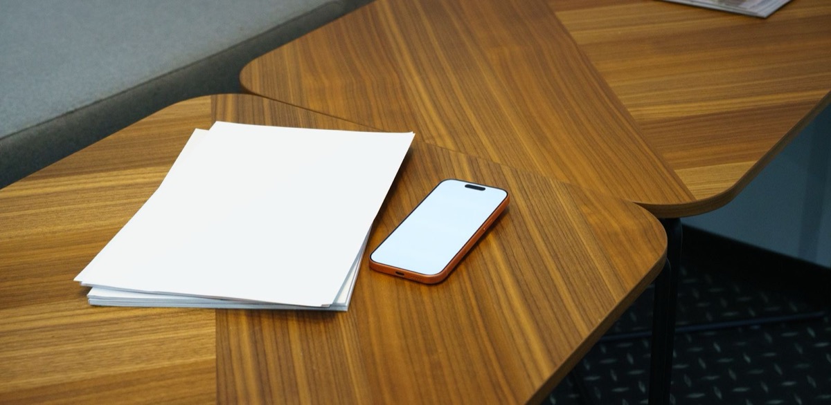 A stack of blank sheets and a phone on a wooden table