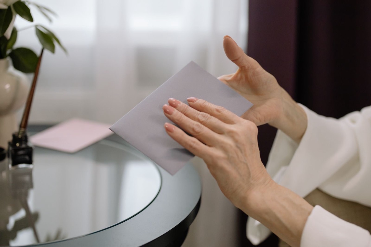Hands holding a grey envelope on a round glass table