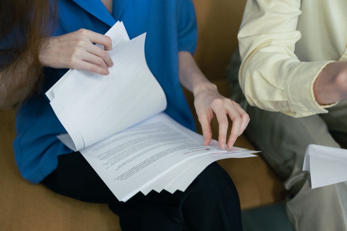 A person turning the pages of a stack of printed documents