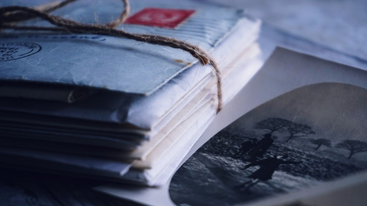 A bundle of papers tied with twine on a blue-tinted surface, with a vintage photograph beside it